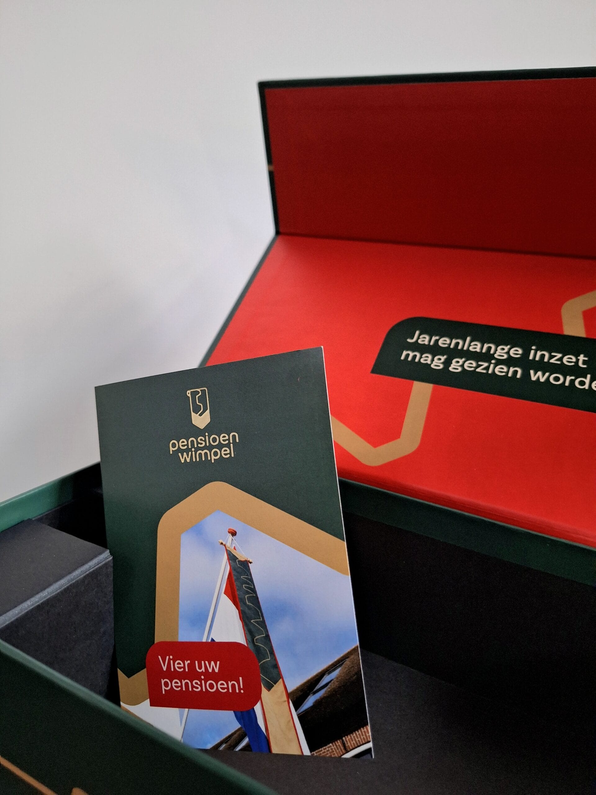 Brochure in de magneetdoos. Vier het pensioen met de pensioenwimpel. Het traditionele pensioencadeau.